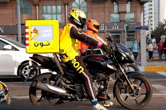 Dubai, Vereinigte Arabische Emirate Mann auf einem Motorrad für Online-Lieferungen.