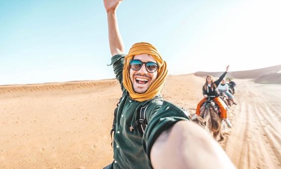 Glücklicher Tourist genießt Kamelritt in der Wüste.
