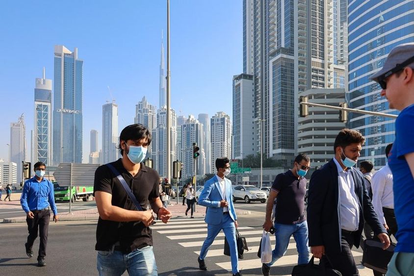 Emberek sétálnak a gyalogátkelőhelyen a dubaji üzleti központban.