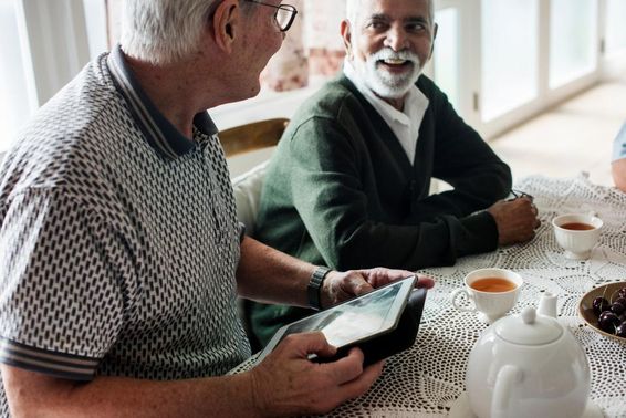 Ältere Freunde schauen gemeinsam auf ein Tablet.