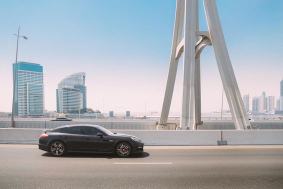 Schwarzer Porsche Panamera fährt auf einer Straße in Dubai.