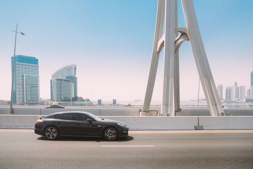 Fekete Porsche Panamera autó mozog a Dubai városi utcán.