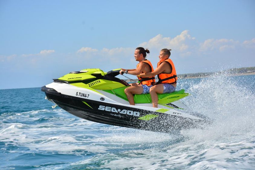 A fiatalember jetski-t vezet és a hullámokon ugrál nyaralás közben.