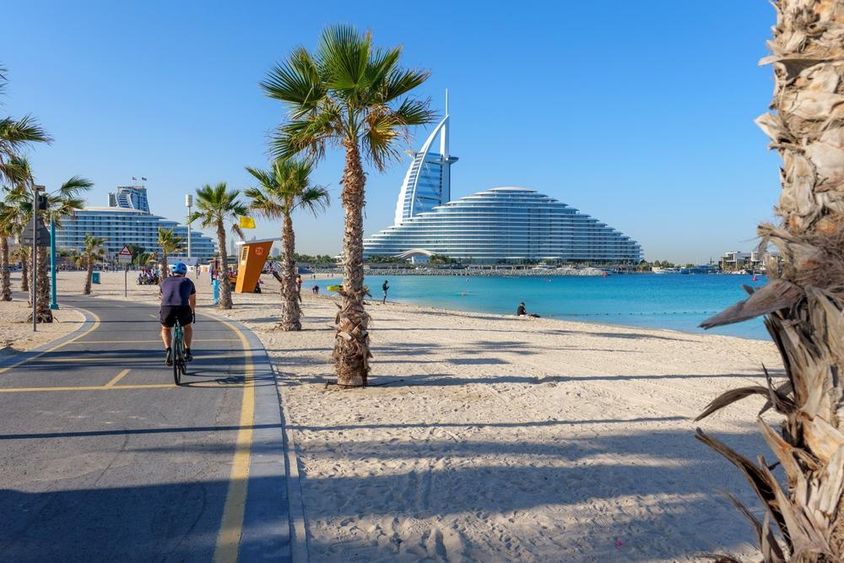Kilátás Burj Al Arabra egy pálmafás kerékpárút mentén Kite Beach Dubai.