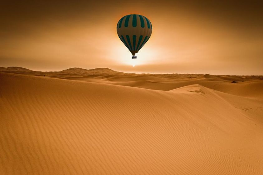 Sivatagi és hőlégballonos táj napkeltekor.