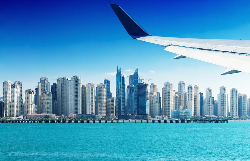 Repülőgép repül Dubai felhőkarcolói felett.