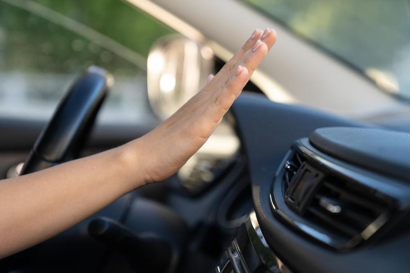 Női kéz ellenőrzi a légkondicionáló panelt az autóban.