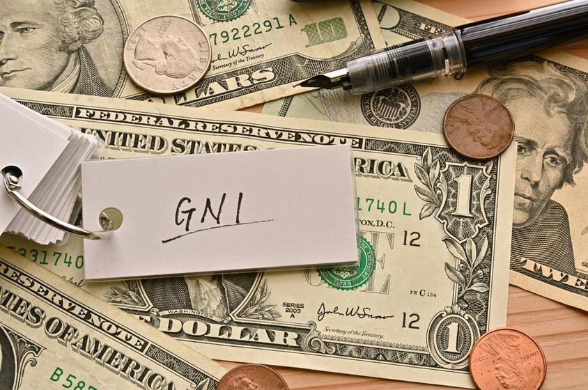 Az asztalon lévő dollárbankjegyek tetején GNI pénzügyi kifejezés van írva.