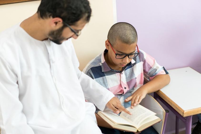 Fiatal arab tanár tanúl egy iskolásfiúval.