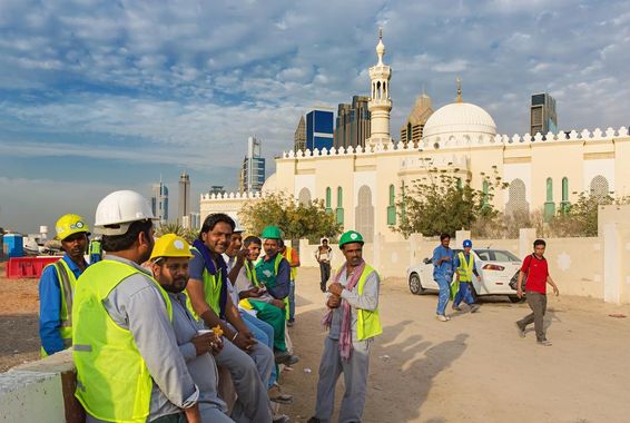 Építőmunkások szünetet tartanak egy mecset mellett a modern Dubai belvárosában.