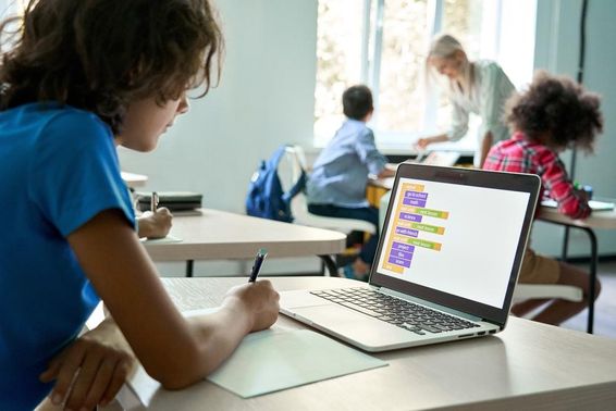 High school student using a laptop to input coding data.