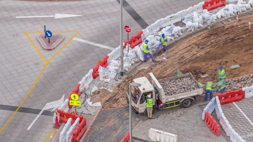 Járdajavítási folyamat sok építőmunkással és berendezéssel, akik járdát és betont bontanak.