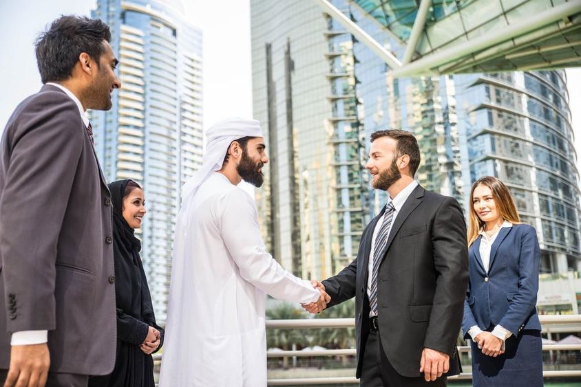 Többnemzetiségű csoport üzletemberek találkozó szabadban Dubaiban.