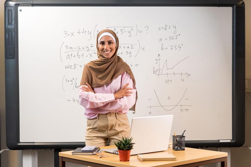 Arab tanárnő hidzsábban áll az osztályteremben.