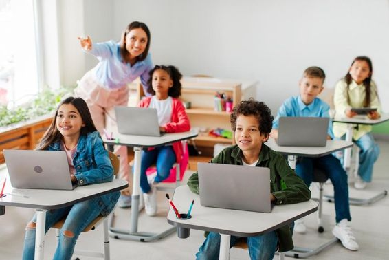 Gyerekek csoportja, akik leckét vesznek, laptopokat használnak.