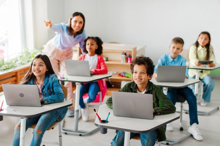 Gyerekek csoportja, akik leckét vesznek, laptopokat használnak.