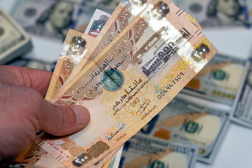 Egy férfi kezében  köteg Egyesült Arab Emírségek 200 kétszáz dirhamos pénz.