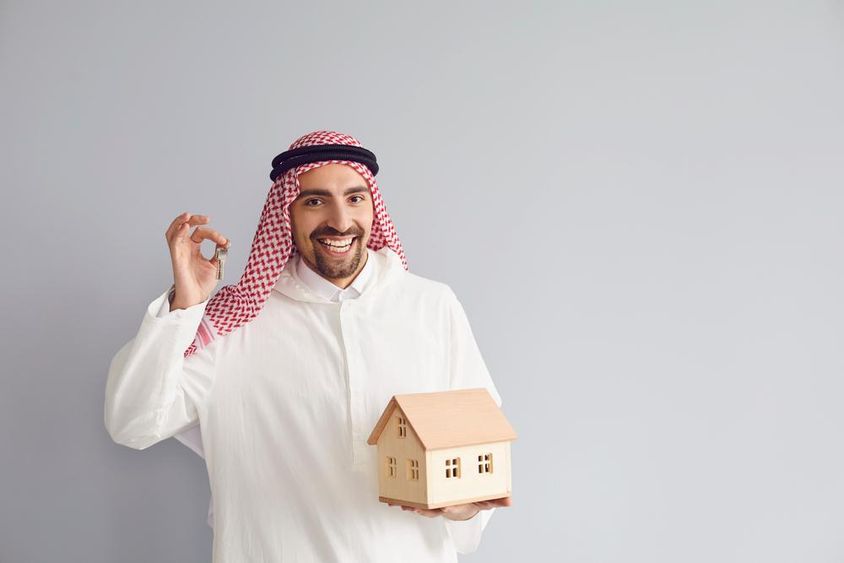 Arab férfi ingatlanügynök faház makettel a kezében.