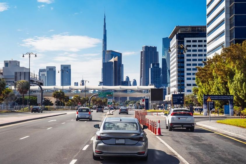 Dubai városi utcán autók mennek.