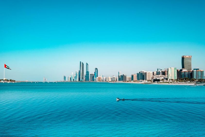 Abu Dhabi vízpartjának látképe egy átkelő halászhajóval.