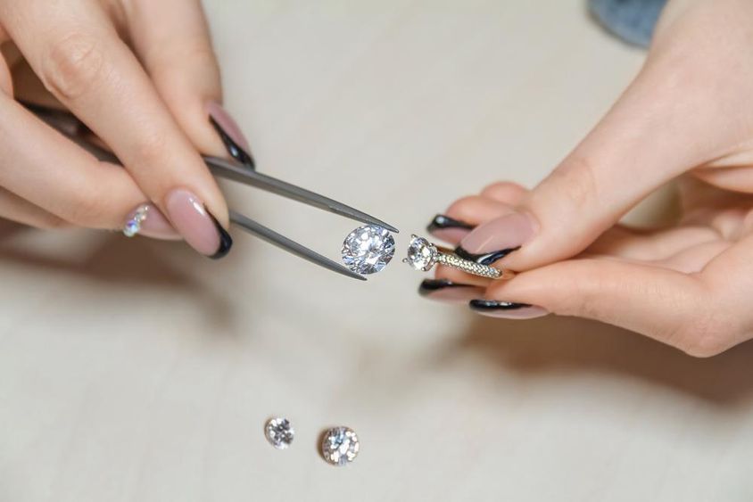 A jeweler's woman's hands holding a gemstone.