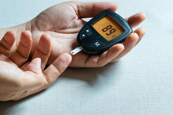 Man's hands using a digital blood glucose meter to monitor diabetes.