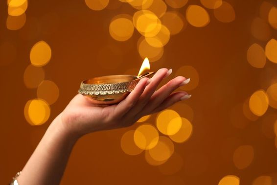 Nő tartja a kezében a megvilágított Diwali lámpát