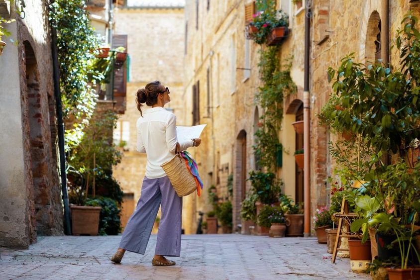 A woman with a map and a straw hat, enjoying the promenade in Tuscany, Italy.