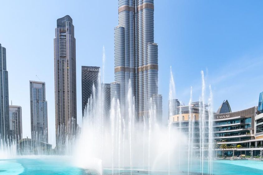 View of the Dubai Fountain and the tall skyscraper, Burj Khalifa, on a sunny day in Dubai.
