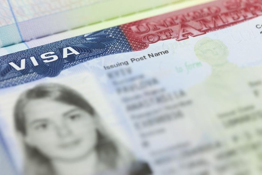U.S. visa on a passport page (USA) in the background.