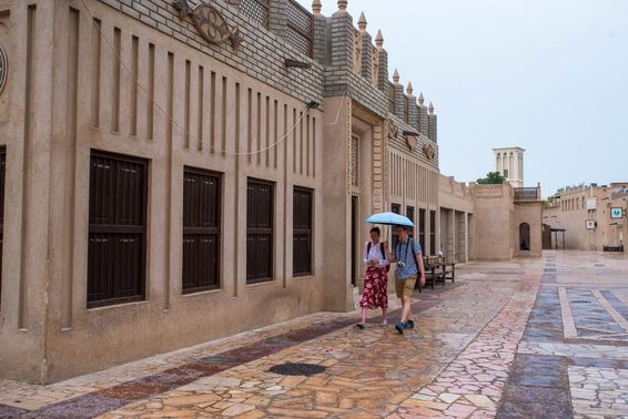 Egy turista pár sétál egy esernyő alatt Dubai utcáin.