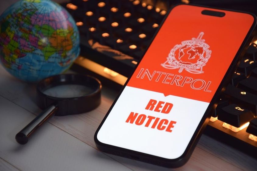 A képernyőn megjelenő, Interpol logóval rendelkező okostelefon.
