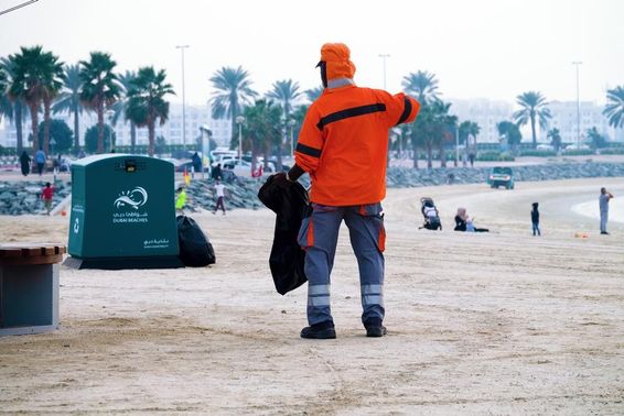 Dubai, Egyesült Arab Emírségek, munkás takarít a strandon.