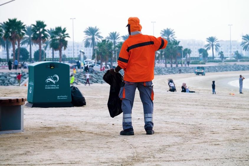 Dubai, Egyesült Arab Emírségek, munkás takarít a strandon.