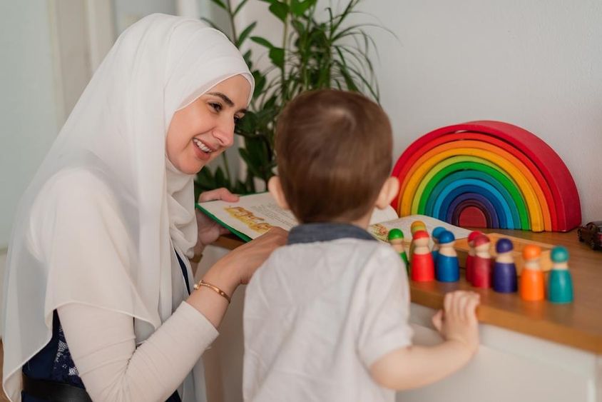 Egy muszlim tanár és egy óvodáskorú gyermek színes játékokkal játszanak.