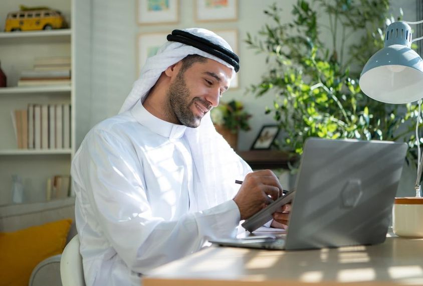 Fiatal arab üzletember otthon dolgozik laptopon.