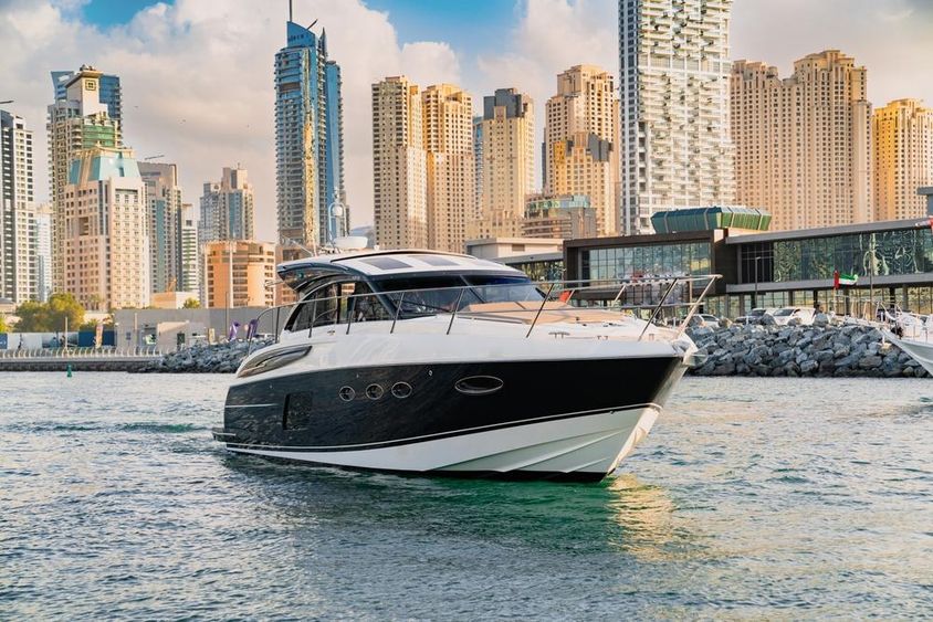 Egy luxusjacht Dubaiban látképpel és felhőkarcolókkal.