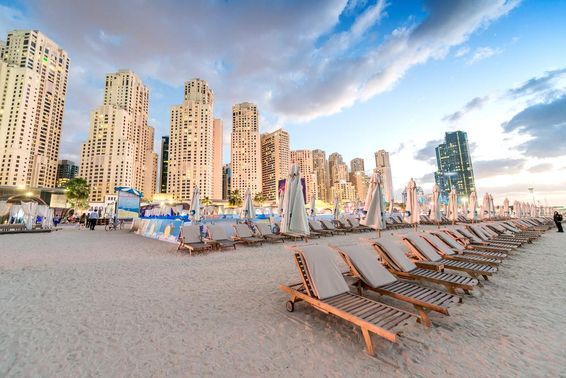 Naplemente a Marina Beachen, Dubaiban, strandszékekkel és felhőkarcolókkal.
