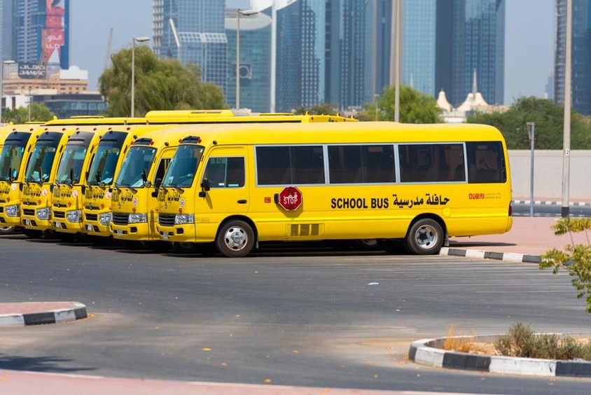 Line of yellow Dubai school buses parked outside.