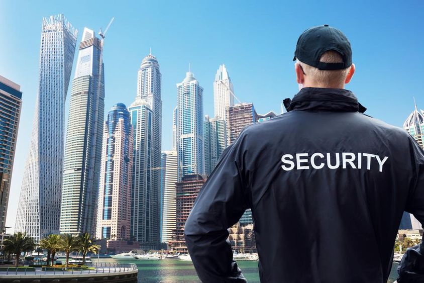 Male security guard watching city skyline from behind.