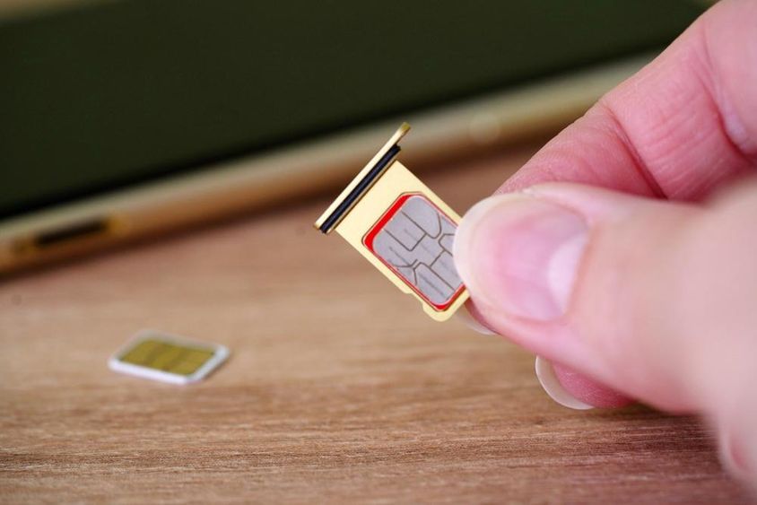 Person inserting a SIM card into the back of a mobile phone.