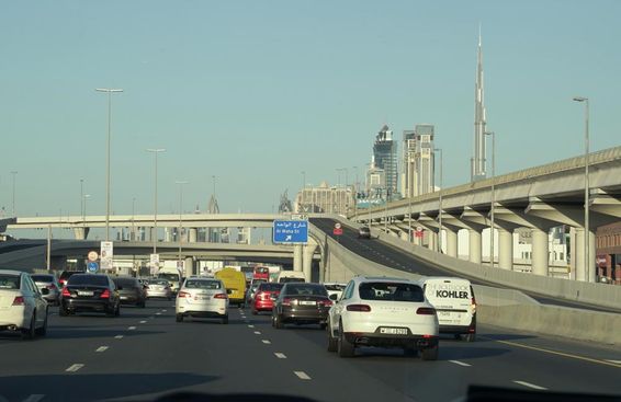 Forgalmi dugó a csúcsforgalomban Dubaiban és Dubai híres felhőkarcolói a háttérben.