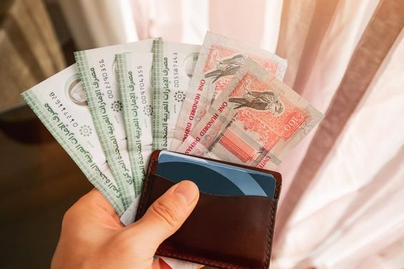 Dirham bankjegyek a kézben és a pénztárca.