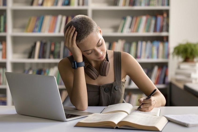 Left-handed teenage girl high school student prepares for university entrance.