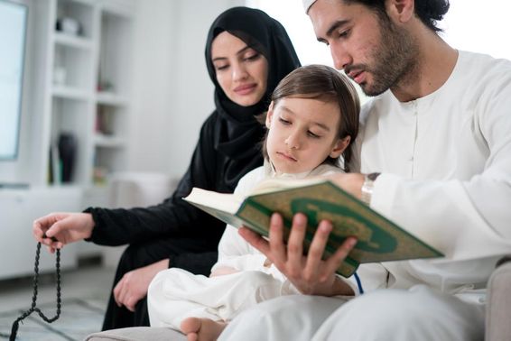 Fiatal szülők a kisfiukkal, akinek Koránt olvasnak a ramadán idején.