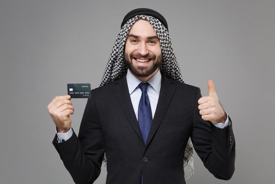 Mosolygó arab muszlim üzletember hitelkártyával.