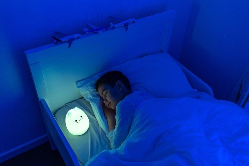 garçon dormant avec lampe LED de chevet.