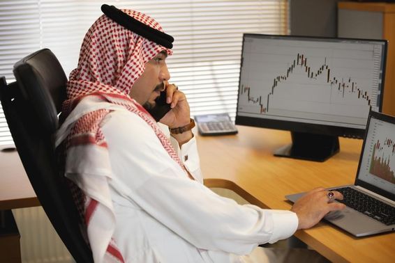 Arab férfi laptopon dolgozik az irodában, tőzsdét néz 