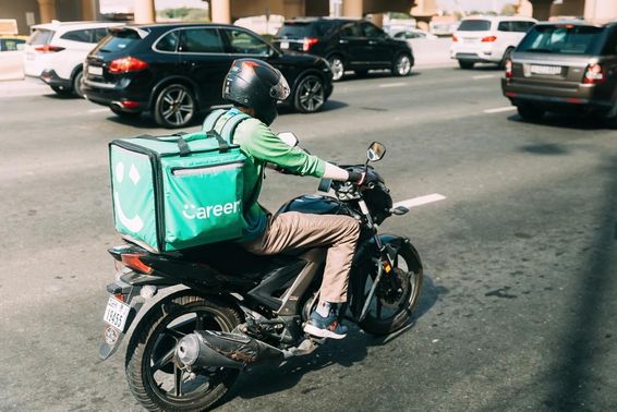 Careem futár robogón ételt szállít. 