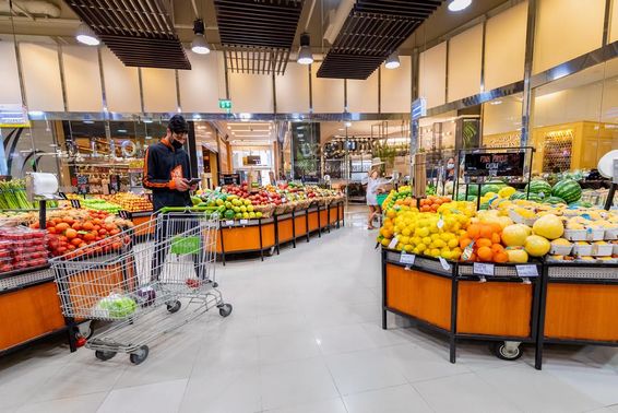 futár zöldségeket és gyümölcsöket válogat egy szupermarketben.